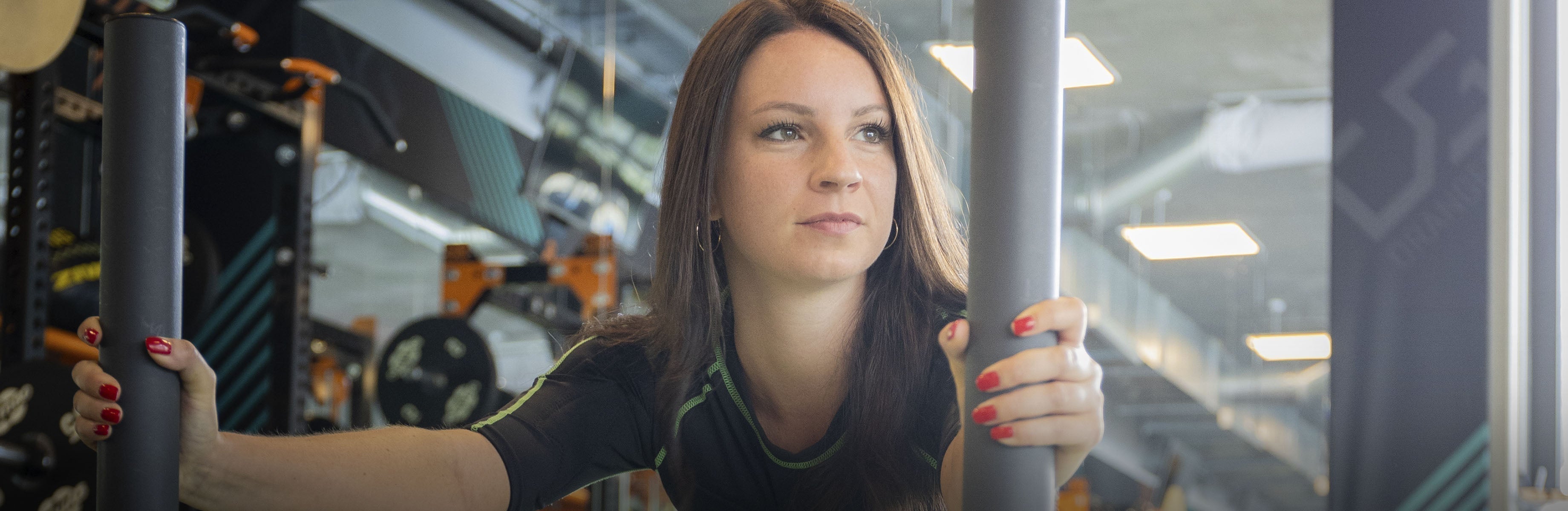 Person im Studio schiebt ein Gewicht vor sich her und blickt dabei rechts am Betrachter vorbei