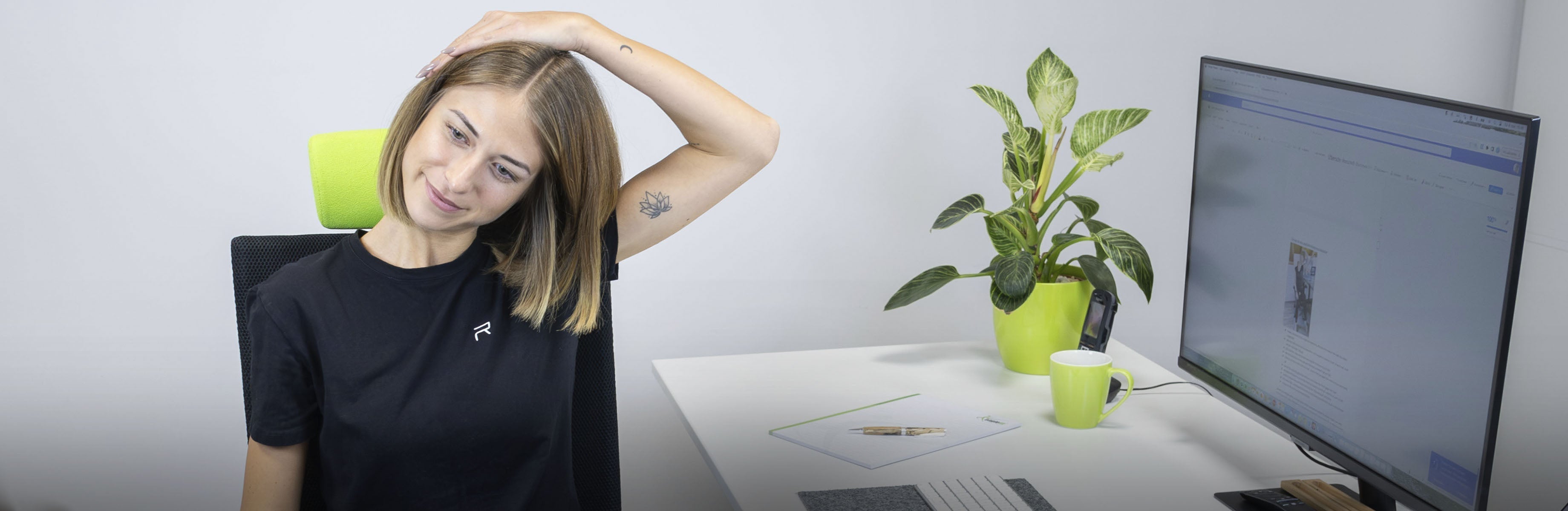 Person sitzt am Arbeitsplatz und dehnt ihren Nacken