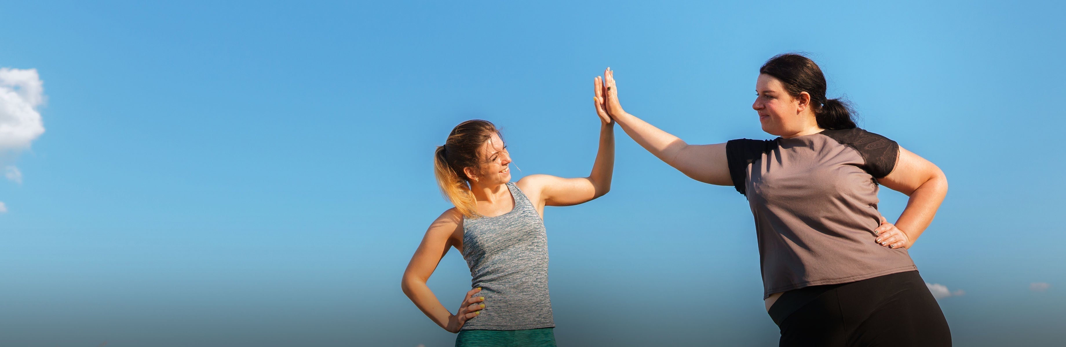 Zwei Personen im Freien machen ein High-Five vor blauem Himmel